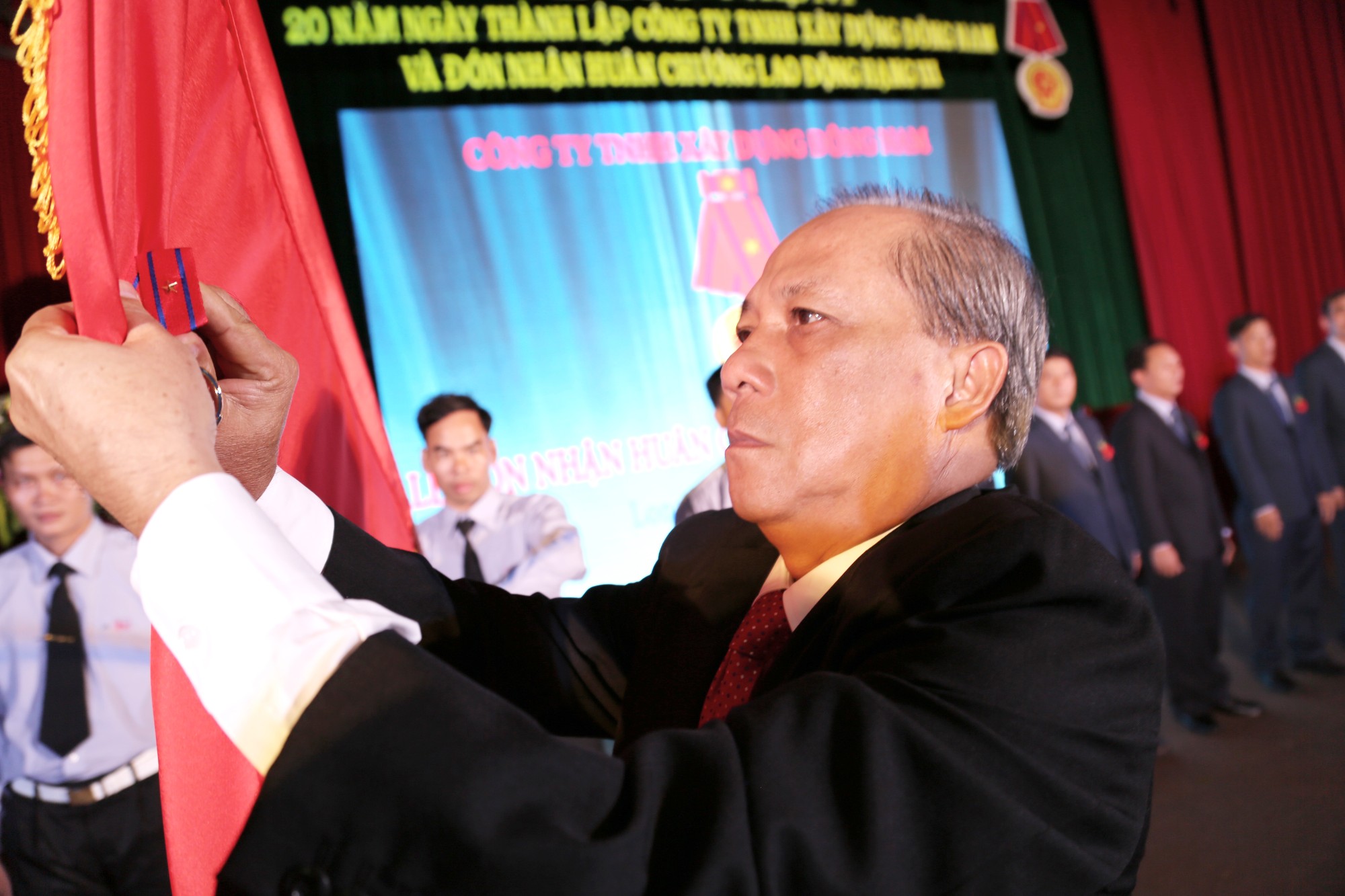Ông Nguyễn Tuấn Minh, Ủy viên trung ương Đảng, Bí thư Tỉnh ủy gắn Huân chương Lao động hạng ba lên cờ truyền thống của Công ty TNHH Xây dựng Đông Nam.